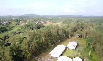 Aerial shot including woods and agricultural buildings